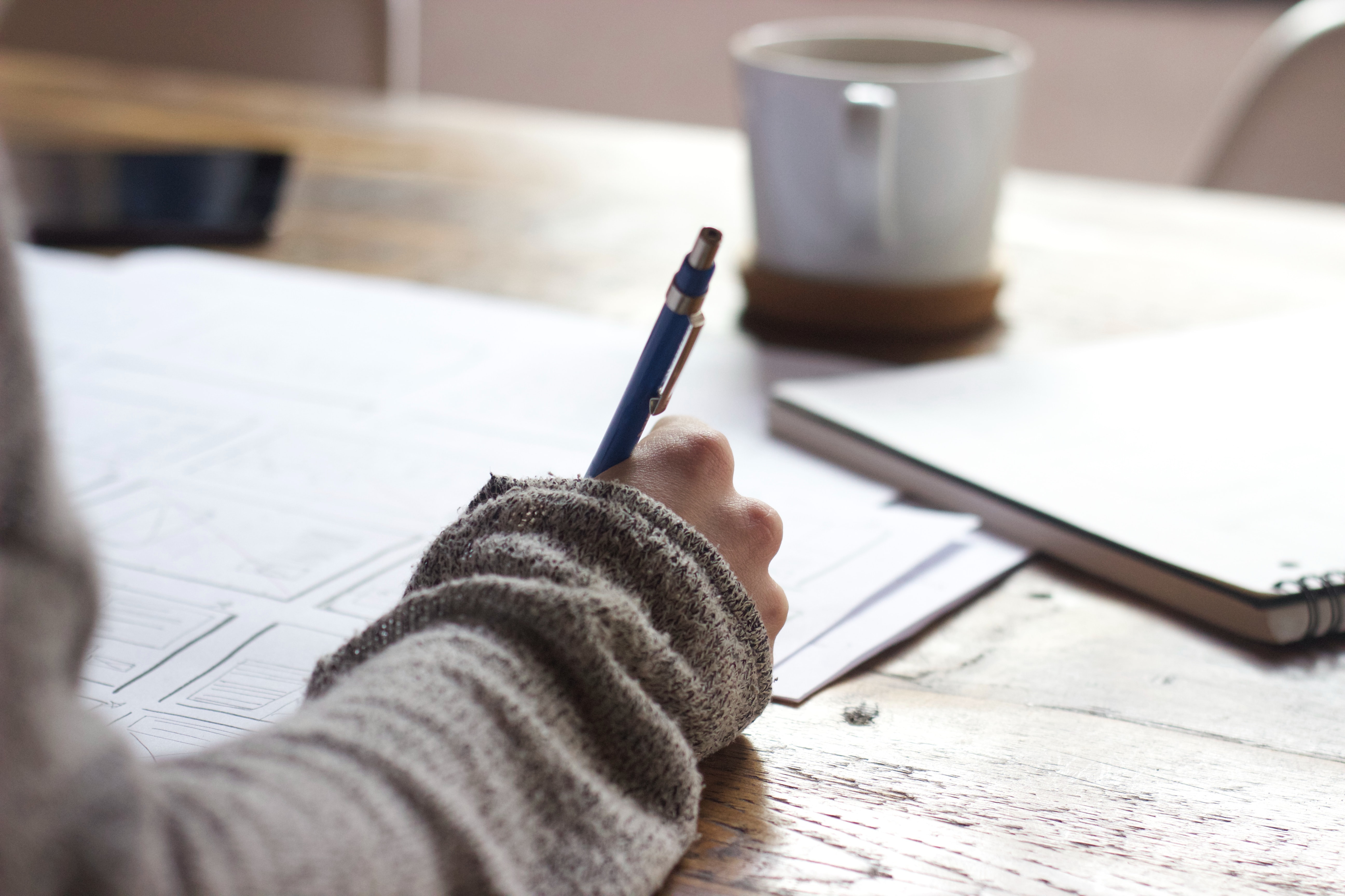 A person sits and writes with pen and paper